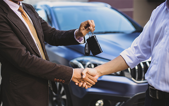 Salesperson handing over car keys to a customer while shaking hands, illustrating successful car sales to boost profits.