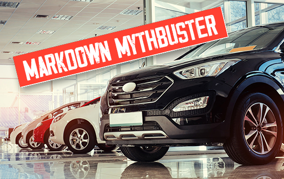 A new car sits on the showroom floor of a dealership. A text "Markdown Mythbuster" is layered over the image.