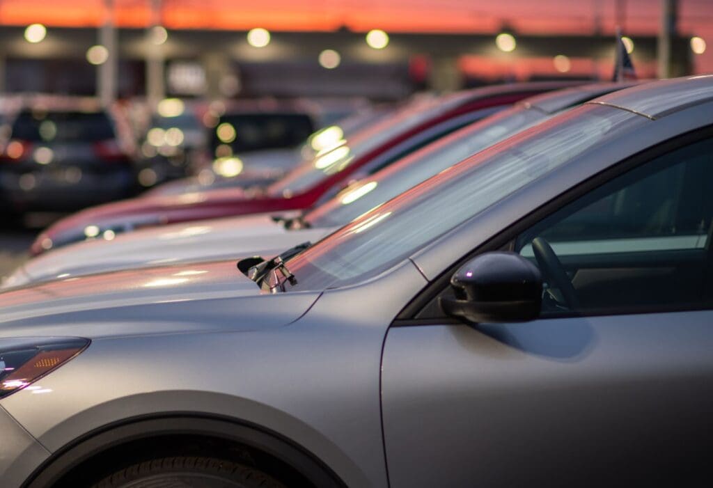 A row of gleaming new cars showcased in a modern dealership showroom. It shows dealer has a successful partnership with a dealership inventory management.