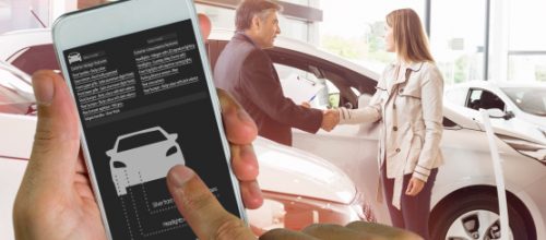 A person using a smartphone with a car inventory app while a salesperson and customer shake hands in a dealership.