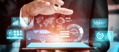 A businessman interacts with a futuristic tablet displaying automotive analytics, data charts, and a holographic car interface.